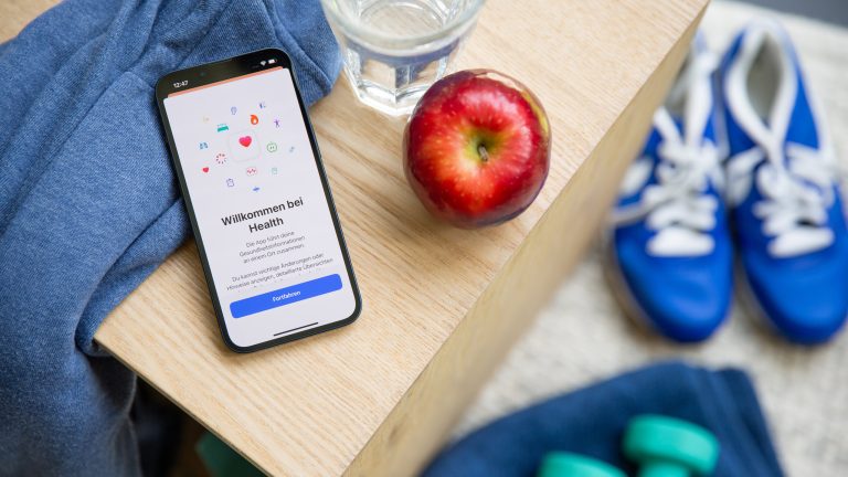 Auf einem Holztisch liegt ein iPhone. Darauf ist die Health App geöffnet.