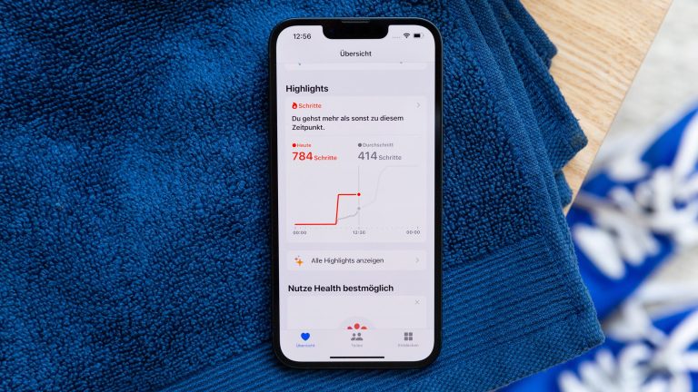 Apple Health richtig nutzen: Gesund leben mit der App Auf einem blauen Handtuch liegt ein iPhone, darauf werden die gelaufenen Schritte als Highlight in der Health App hervorgehoben.